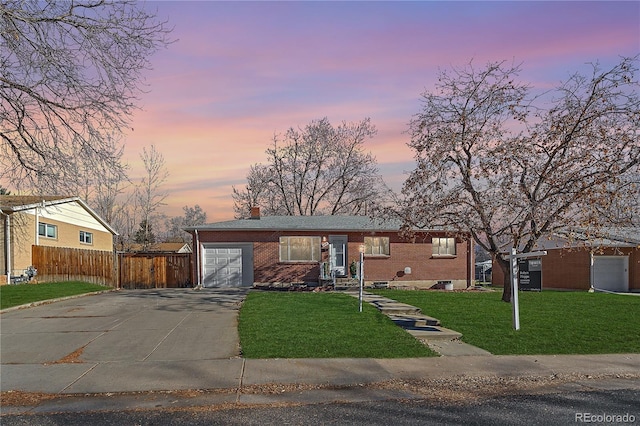 ranch-style home featuring a garage and a yard