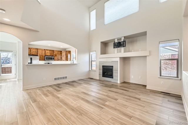 unfurnished living room with a healthy amount of sunlight, visible vents, a fireplace, and light wood finished floors