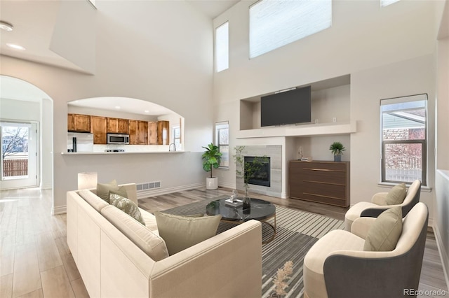 living room with light wood-type flooring, visible vents, plenty of natural light, and a tiled fireplace