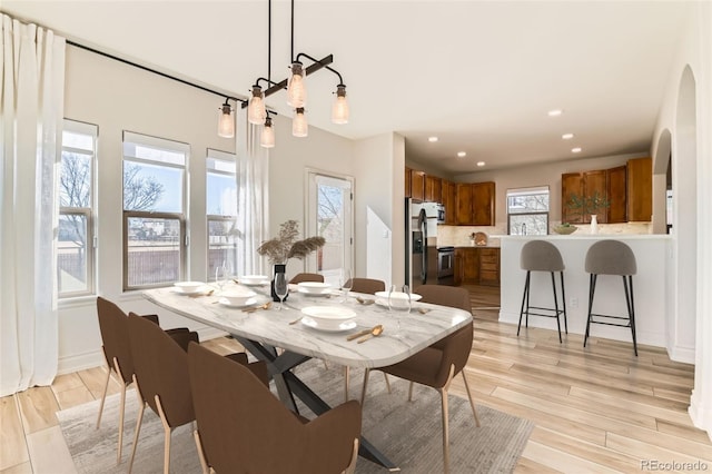 dining room featuring light wood-style floors, arched walkways, and recessed lighting