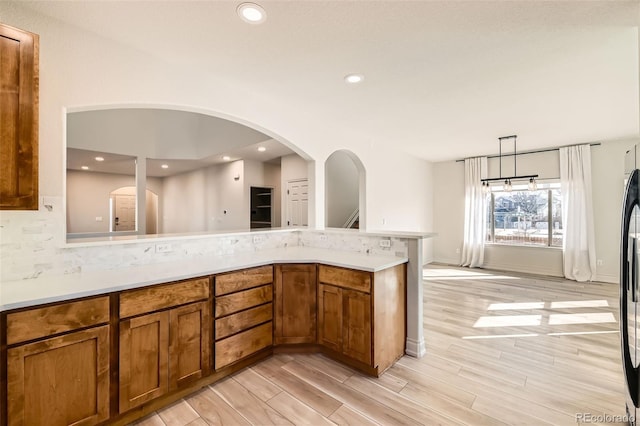 kitchen featuring light countertops, light wood finished floors, brown cabinetry, and recessed lighting