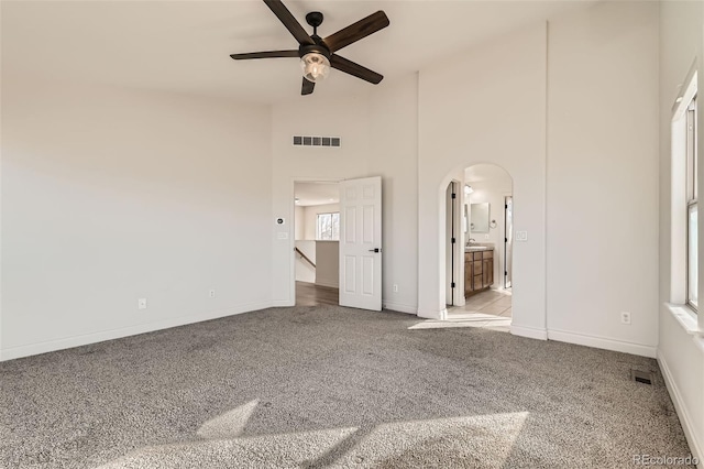 unfurnished bedroom featuring light carpet, arched walkways, visible vents, and baseboards