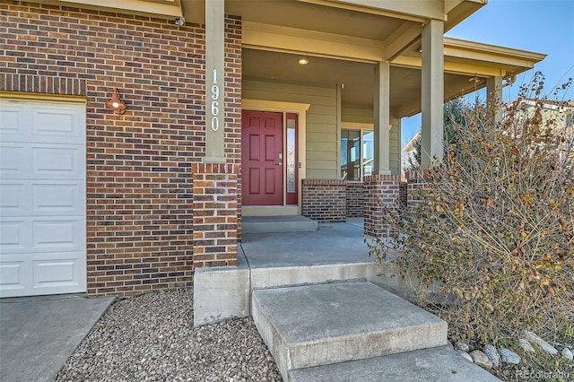 property entrance with a garage, brick siding, and a porch