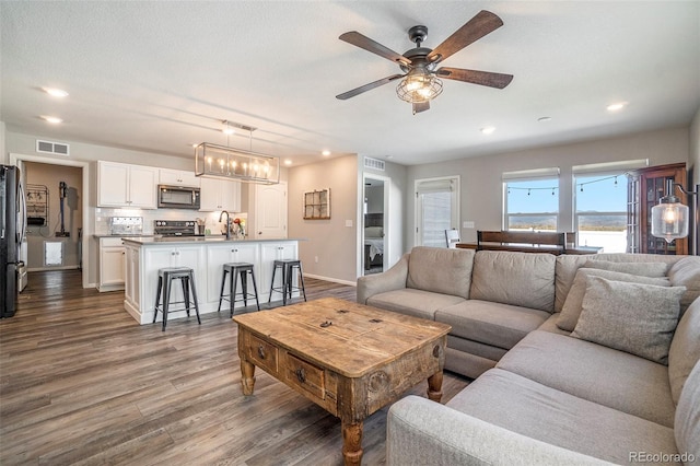 living room featuring ceiling fan, dark hardwood / wood-style flooring, and sink