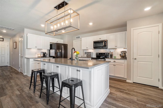 kitchen with white cabinets, a center island with sink, and appliances with stainless steel finishes