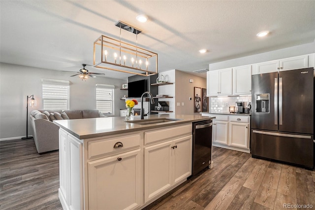 kitchen featuring sink, a center island with sink, stainless steel fridge, and white cabinetry