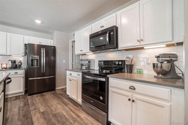 kitchen with white cabinets, dark hardwood / wood-style floors, backsplash, and appliances with stainless steel finishes