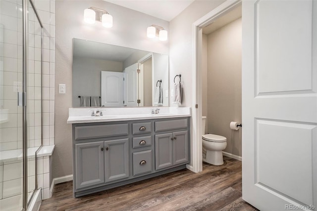 bathroom featuring toilet, wood-type flooring, vanity, and walk in shower