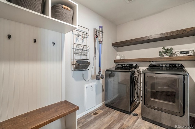 washroom with washing machine and clothes dryer and light hardwood / wood-style floors