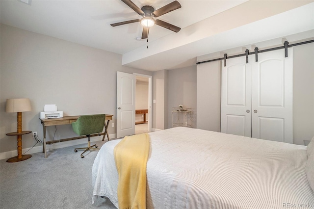 carpeted bedroom featuring a barn door, ceiling fan, and a closet