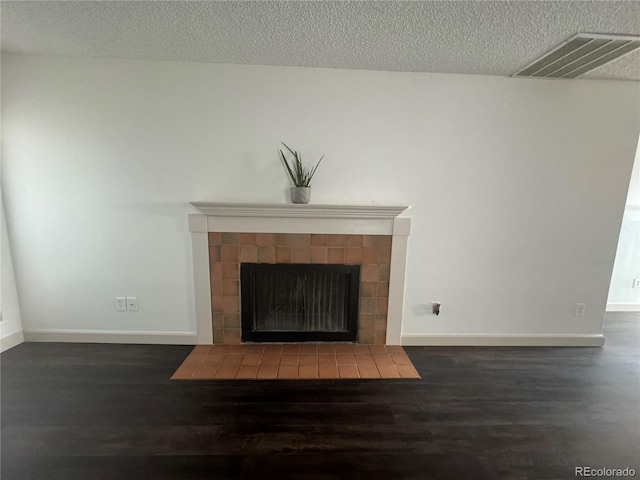 room details featuring wood-type flooring, a tiled fireplace, and a textured ceiling