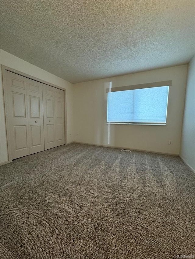 unfurnished bedroom featuring carpet floors, a textured ceiling, and a closet