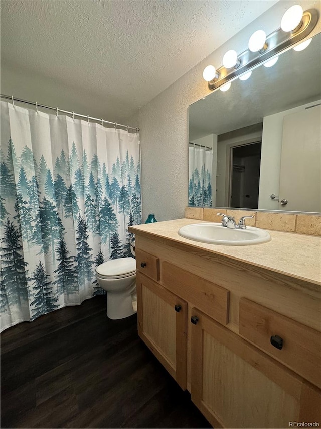 bathroom with a textured ceiling, hardwood / wood-style flooring, vanity, and toilet