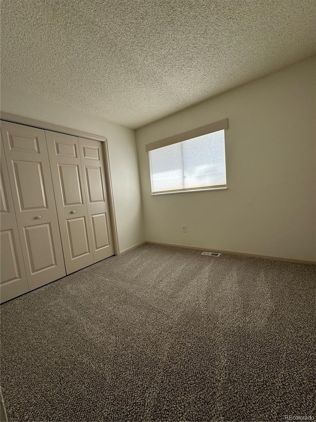 unfurnished bedroom featuring a closet, carpet floors, and a textured ceiling