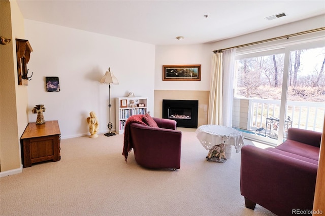 living room with carpet floors, baseboards, visible vents, and a glass covered fireplace