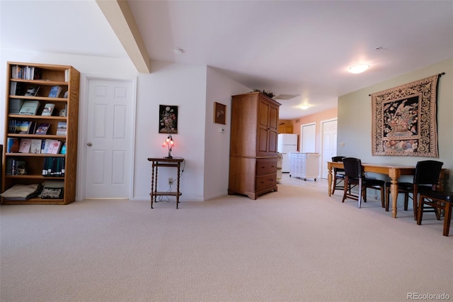 dining space with light carpet and beamed ceiling