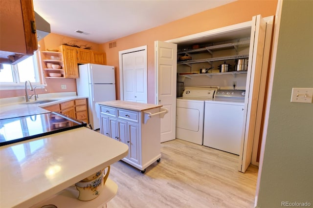 kitchen with washing machine and clothes dryer, open shelves, visible vents, freestanding refrigerator, and a sink