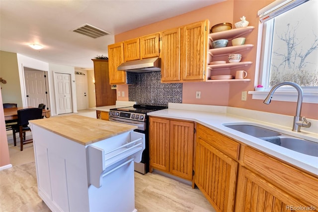 kitchen featuring under cabinet range hood, a kitchen island, a sink, visible vents, and stainless steel electric stove