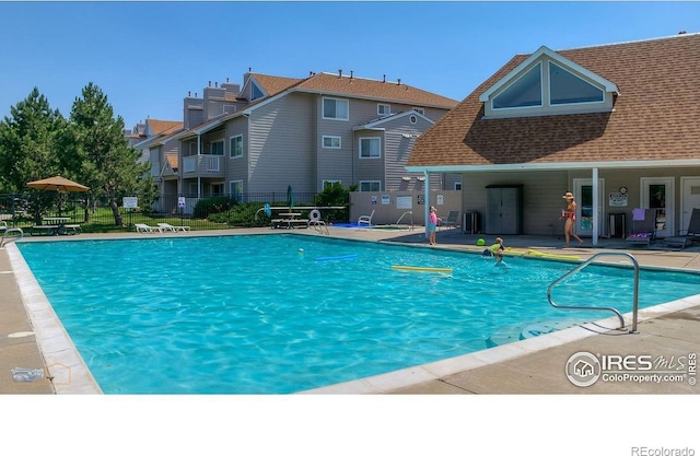 community pool featuring a patio area, fence, and cooling unit