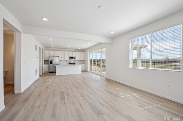 unfurnished living room with light wood finished floors, visible vents, and baseboards