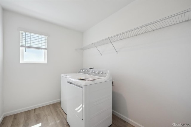 laundry area with light wood finished floors, laundry area, baseboards, and washing machine and dryer