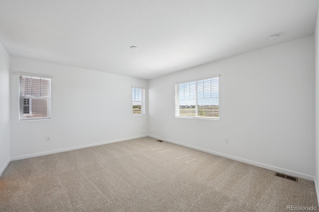 empty room with light colored carpet, baseboards, and visible vents