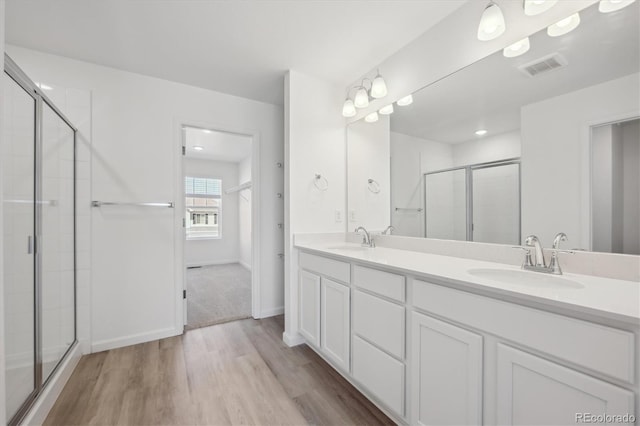 full bathroom featuring a shower stall, visible vents, a sink, and wood finished floors