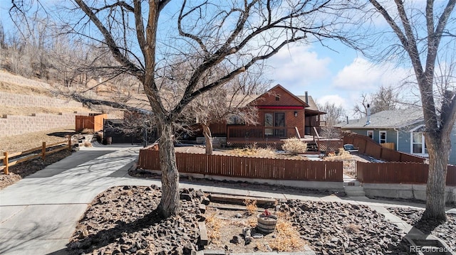 view of front of home with a fenced front yard, a deck, and concrete driveway