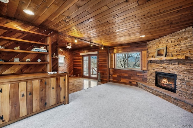 living area with light carpet, wooden ceiling, a fireplace, and wooden walls