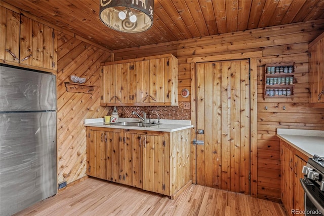 kitchen with a sink, brown cabinets, stainless steel appliances, and light countertops