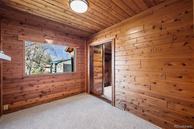 carpeted spare room featuring wooden ceiling and wood walls