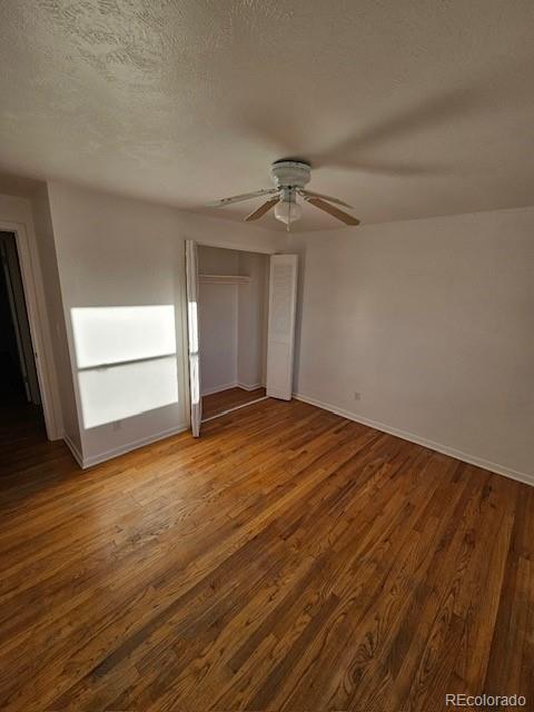 unfurnished bedroom with ceiling fan, a textured ceiling, a closet, and hardwood / wood-style floors