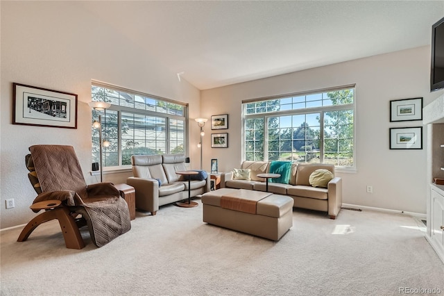 living area with lofted ceiling, a healthy amount of sunlight, light colored carpet, and baseboards