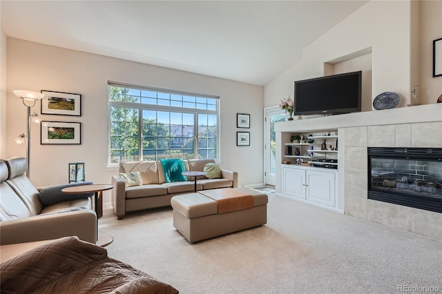 living room featuring lofted ceiling, a fireplace, and light colored carpet