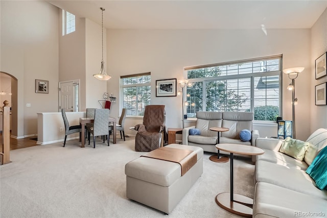 living room with arched walkways, carpet floors, high vaulted ceiling, and baseboards