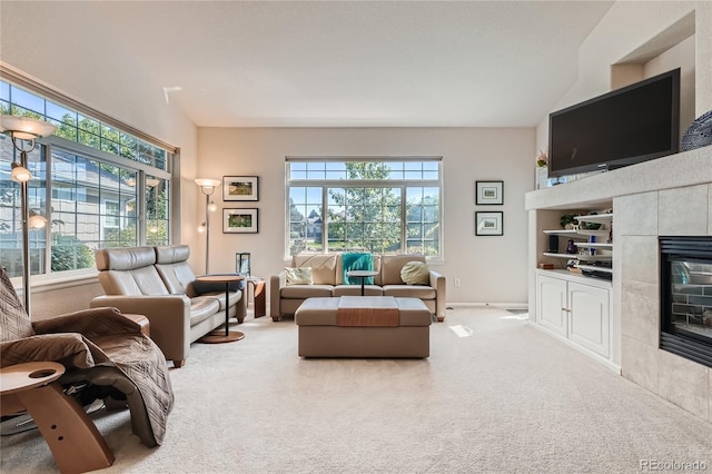 living room with built in shelves, lofted ceiling, light carpet, a tile fireplace, and baseboards