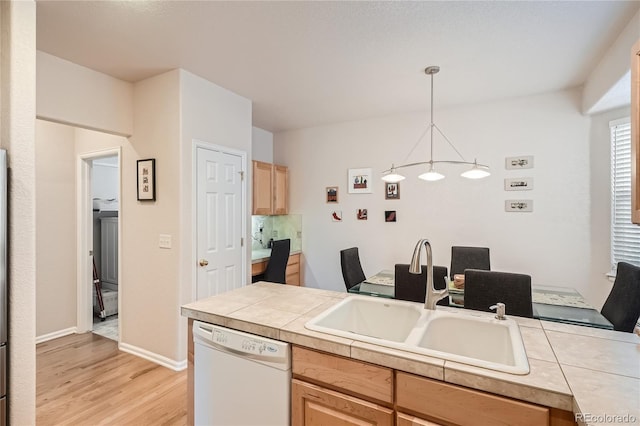 kitchen featuring light wood finished floors, baseboards, dishwasher, pendant lighting, and a sink