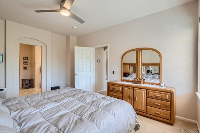 bedroom with ceiling fan, arched walkways, baseboards, and light colored carpet