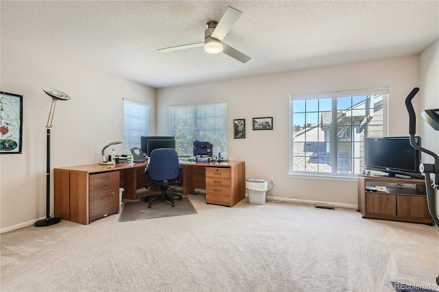 office area with a textured ceiling, baseboards, a ceiling fan, and light colored carpet