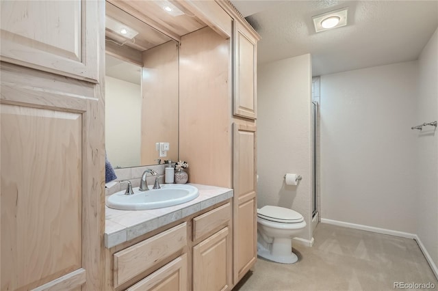 bathroom with toilet, a shower with shower door, vanity, and baseboards