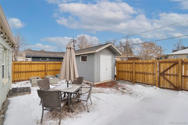 snow covered patio featuring a storage shed