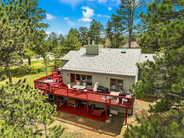rear view of property featuring outdoor dining space, a chimney, and a deck