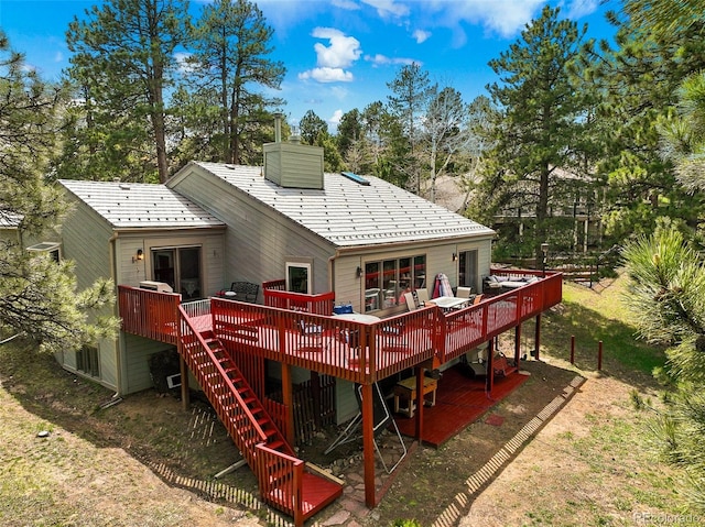 rear view of house with stairway, a wooden deck, and a chimney