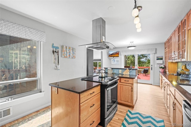 kitchen with visible vents, island range hood, a center island, light wood-style flooring, and stainless steel appliances