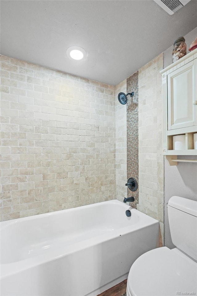 bathroom with toilet,  shower combination, and visible vents
