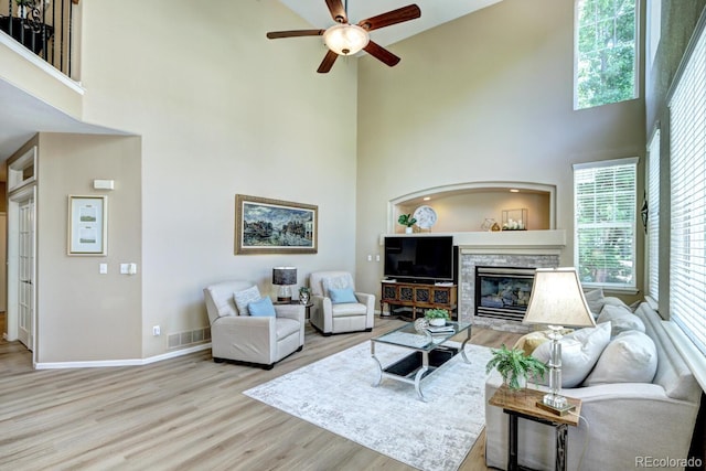 7329 Arco Iris Ln, Castle Pines, CO 80108 - living area featuring a high ceiling, a ceiling fan, wood finished floors, healthy amount of natural light, and a stone fireplace