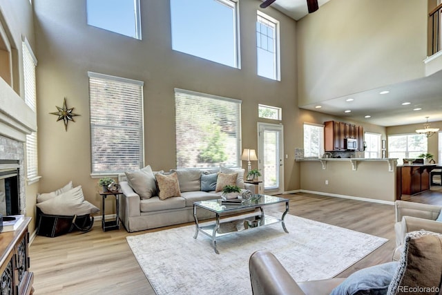 7329 Arco Iris Ln, Castle Pines, CO 80108 - living area featuring a high ceiling, light wood finished floors, ceiling fan, a glass covered fireplace, and recessed lighting