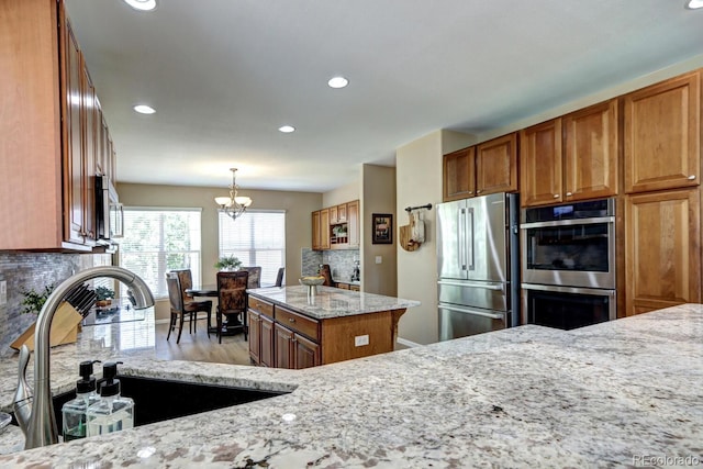 7329 Arco Iris Ln, Castle Pines, CO 80108 - kitchen with stainless steel appliances, brown cabinetry, light stone countertops, decorative backsplash, and recessed lighting