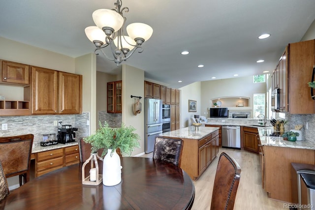 7329 Arco Iris Ln, Castle Pines, CO 80108 - kitchen featuring appliances with stainless steel finishes, brown cabinetry, light wood finished floors, tasteful backsplash, and recessed lighting