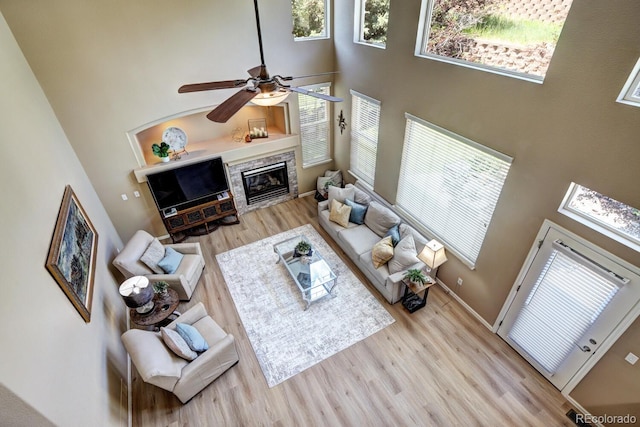 7329 Arco Iris Ln, Castle Pines, CO 80108 - living area featuring a towering ceiling, wood finished floors, healthy amount of natural light, a ceiling fan, and a glass covered fireplace